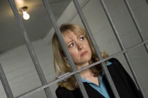 Editors cannot review books they edit, and doing so can cause problems. Image of female professional behind bars.