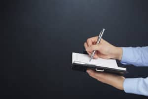 Editors cannot review books they edit. Image of hands holding a book and a pen.