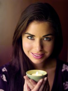 Using scented candles for focus is simple and pleasant, as this woman holding a vanilla candle shows.