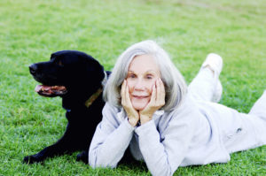This woman on the grass with a dog—is it lay or lie on the grass? The answer is lie.